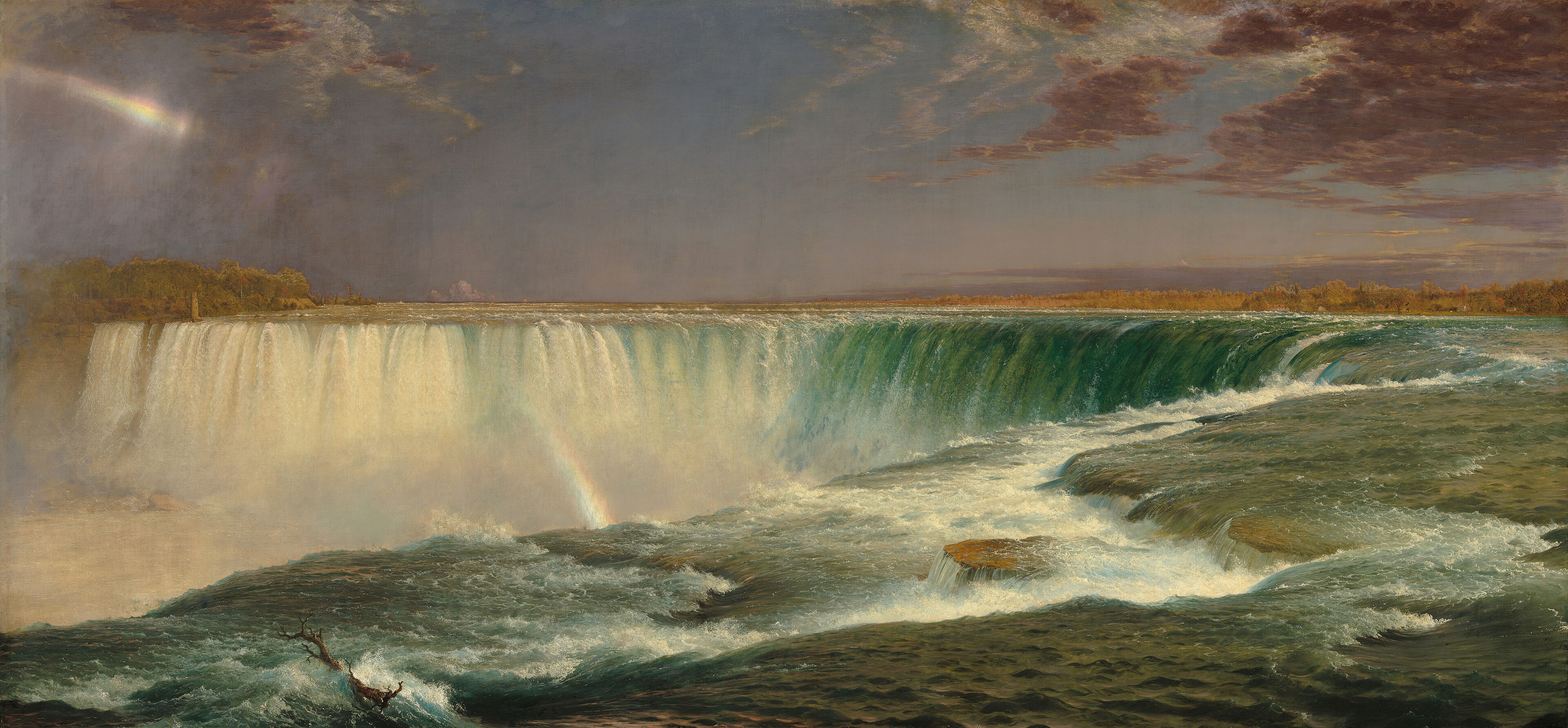 A broad view of Niagara Falls with green rushing water, white mist, and a faint rainbow under a lavender sky.